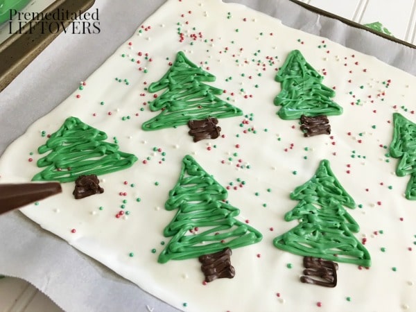 Quick and Easy Christmas Tree Candy Bark Tutorial - Add the trunks by piping dark chocolate at the base of the trees.