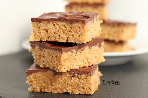 a stack of scotcheroos peanut butter rice krispie treats in front of a plate of treats