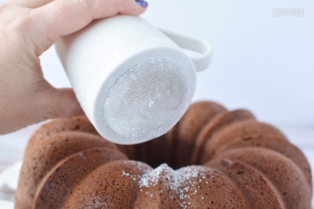 Sprinkling powdered sugar dusting onto the finished bundt cake.