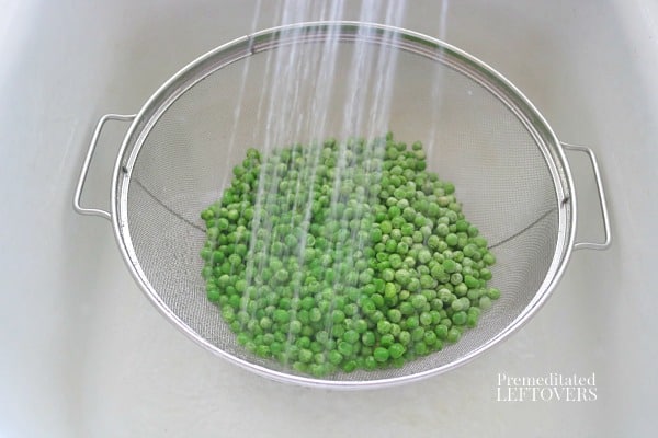 Thawing frozen peas with hot water.