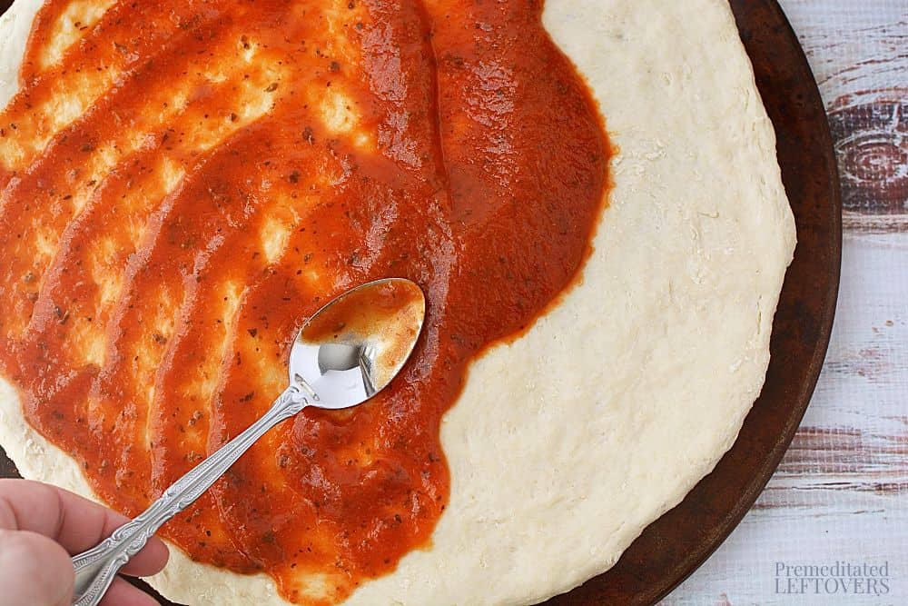 Spreading pizza sauce on the dough