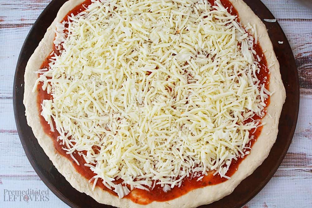 Mozzarella cheese sprinkled on top of the pizza sauce