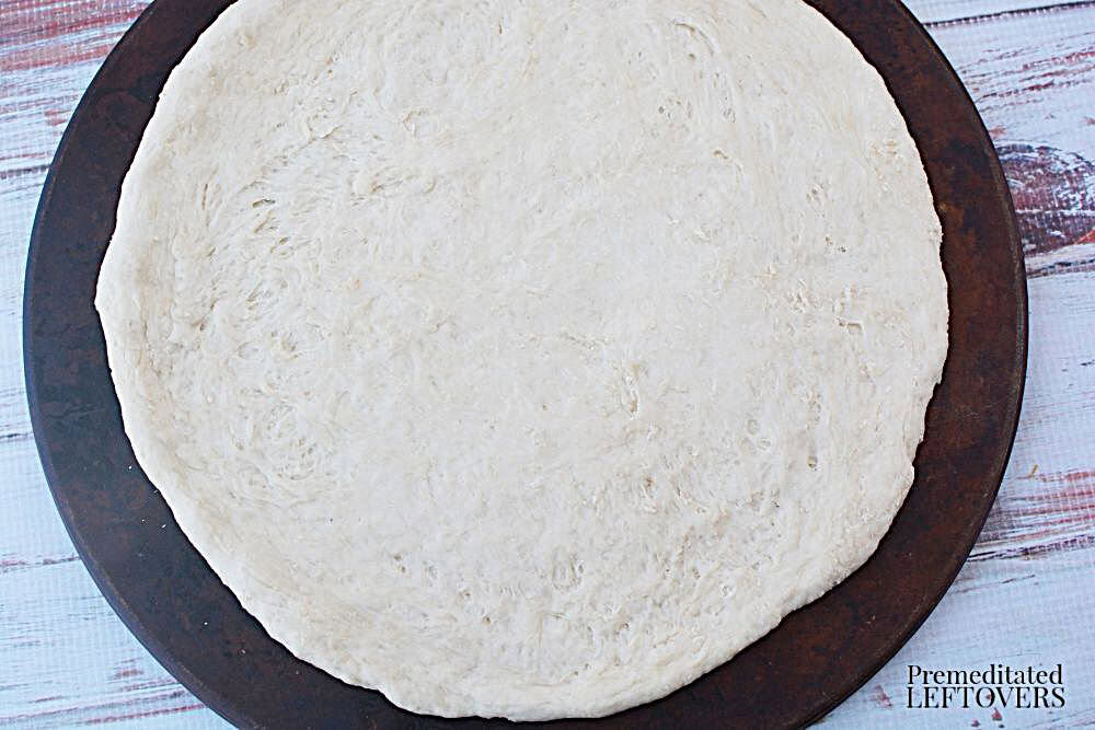 Raw pizza dough on baking stone