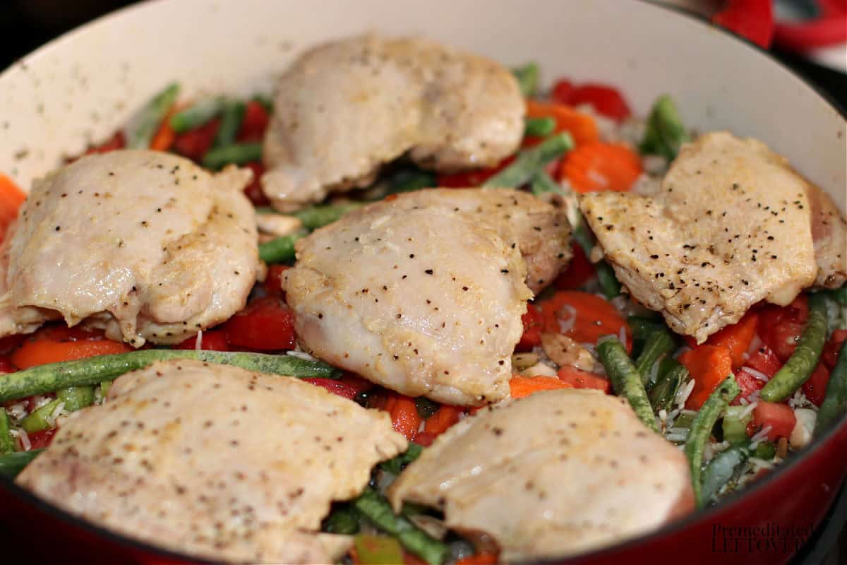 browned chicken thighs placed on top of vegetables and rice