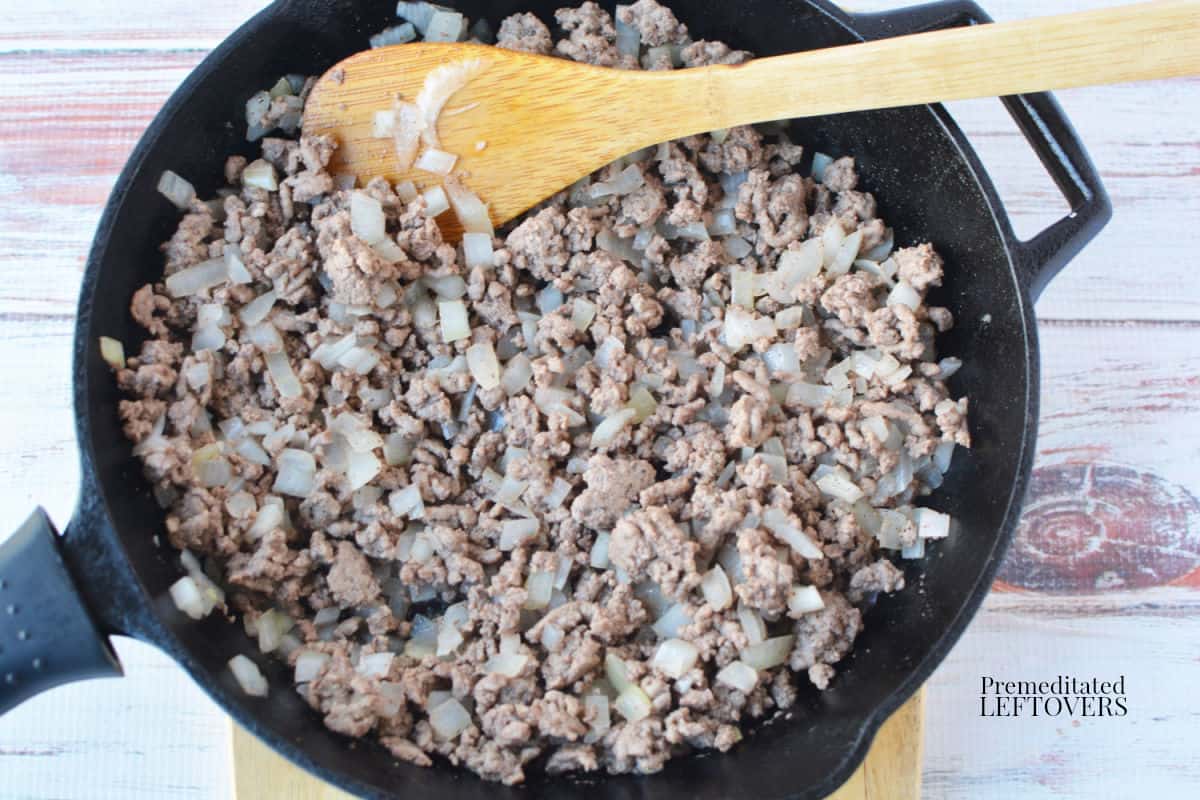 the ground beef cooking with the onions in a frying pan