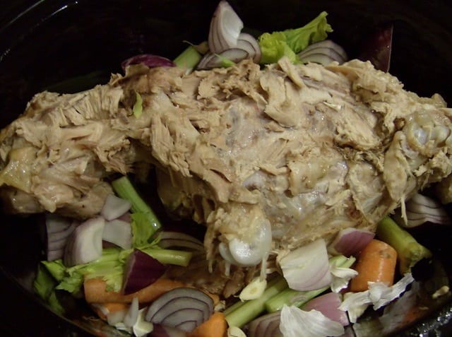 turkey bones in a slow cooker with celery, carrot, and onion
