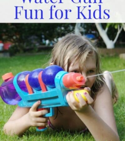 A girl laying on the lawn squirting a water gun.