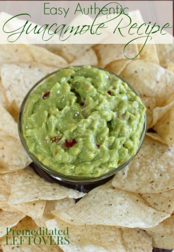 Easy Authentic Guacamole Recipe with diced tomato in a dip bowl with chips.