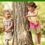 boy and girl playing with sticks by tree -