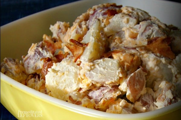 loaded potato salad recipe in bowl topped with bacon and cheese