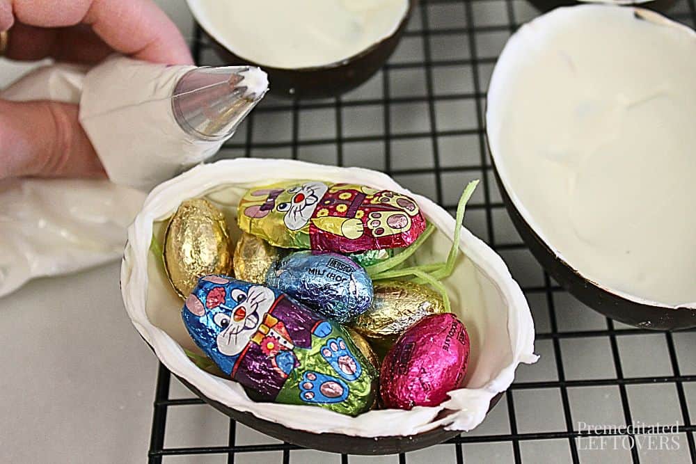 Fill the bottom half of hollow chocolate eggs with candy or treats then pipe icing on edge
