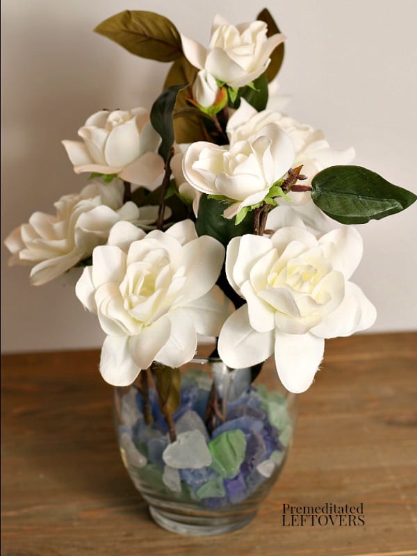 A vase with sea glass in it to hold flower stems in place.