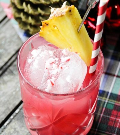 Raise a glass of Christmas cheer! This simple Cranberry, Pineapple, and Peppermint Cocktail recipe is garnished with crushed candy cane and pineapple.