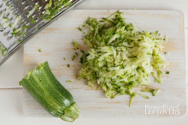shredded zucchini on a cutting board with a metal grater