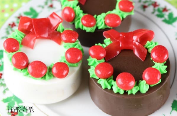 Chocolate covered oreos decorated with frosting and candy to look like a wreath.