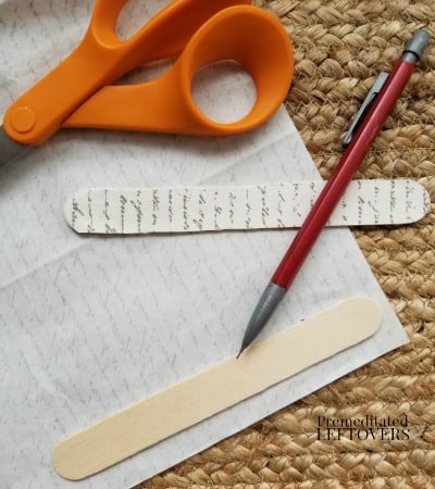 Trace craft sticks on scrap paper to make the cross ornament.