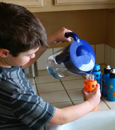 Child filling water bottles with filtered water from Brita Filter Pitcher