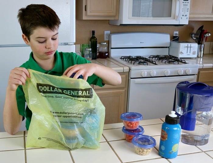 Son placing snacks and water bottles in a Dollar General grocery bag