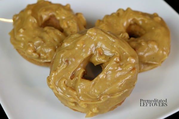 3 peanut butter doughnuts with chunky peanut butter glaze on a plate.