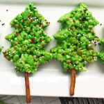 Christmas tree rice krispie treats recipe using a cookie cutter to cut out the Christmas trees from green rice Krispie treats and a pretzel stick for the tree trunk