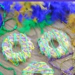 Purple, and green king cake rice krispie treats on a tray with a boa