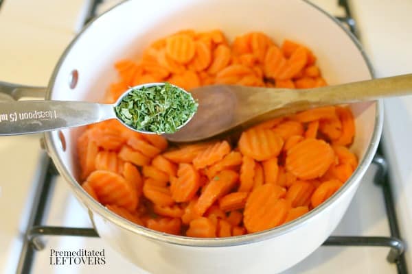 Adding dried parsley to the cooked carrots.