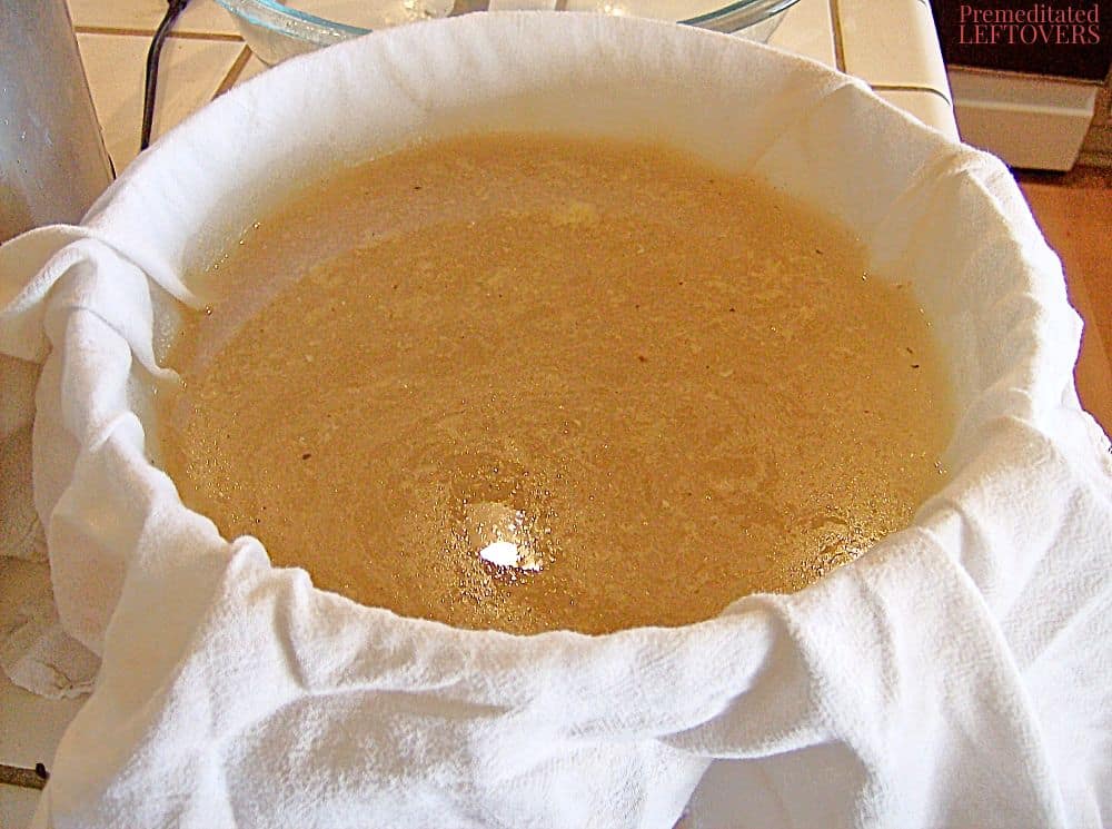 Filtering chicken broth through a flour sack towel.