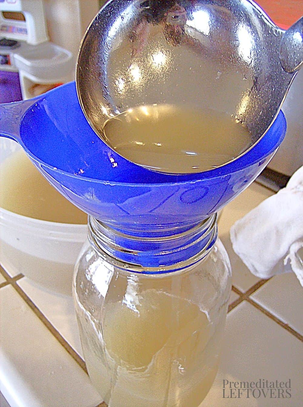 ladling chicken broth into jars