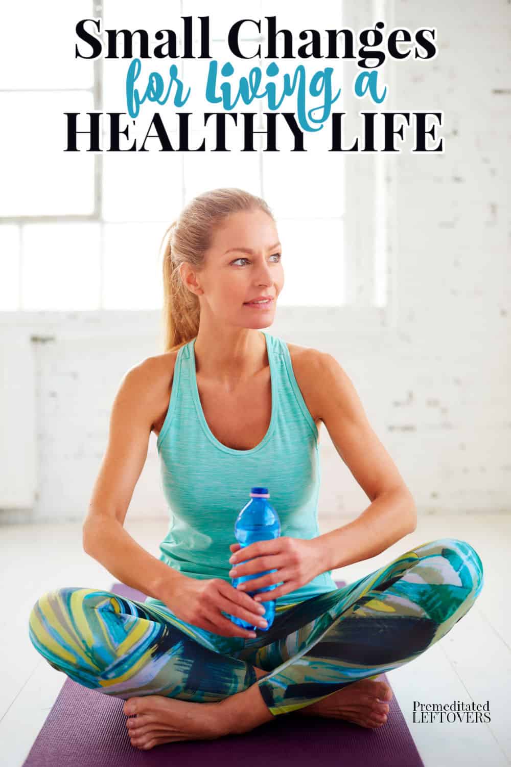woman sitting on yoga mat holding a bottle of water