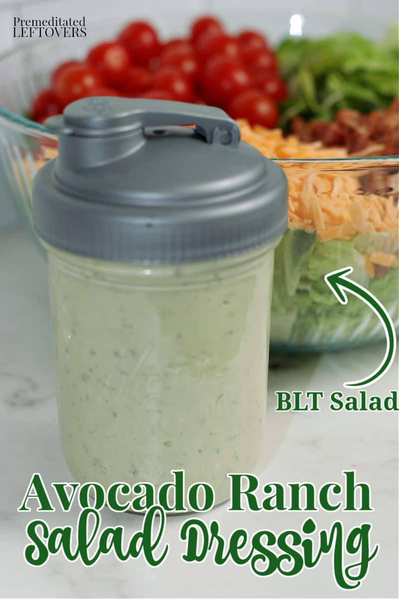 Avocado ranch salad dressing recipe in a mason jar in front of a bowl of salad.