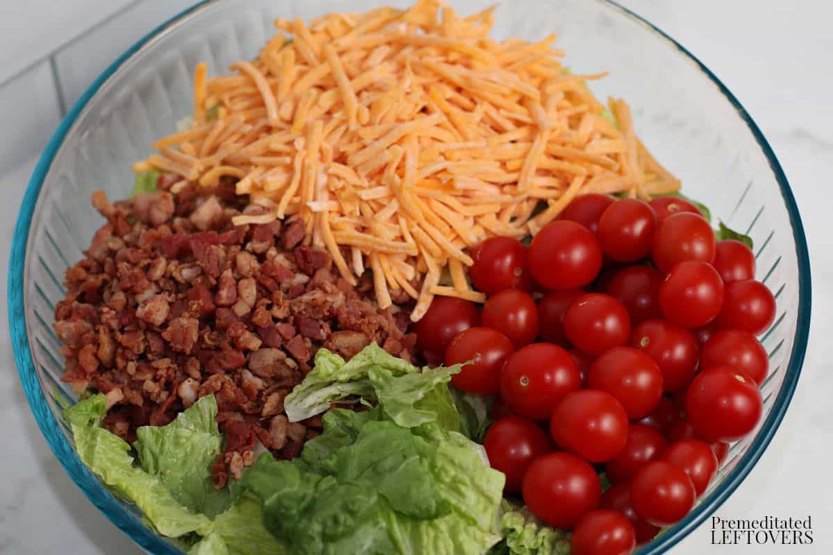 BLT salad ingredients (bacon, lettuce, cherry tomatoes, and cheese) in a large bowl.