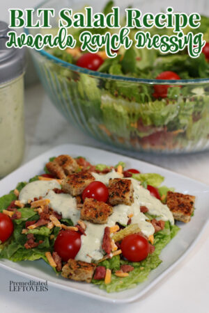 A BLT salad on a white plate with avocado ranch dressing and croutons.