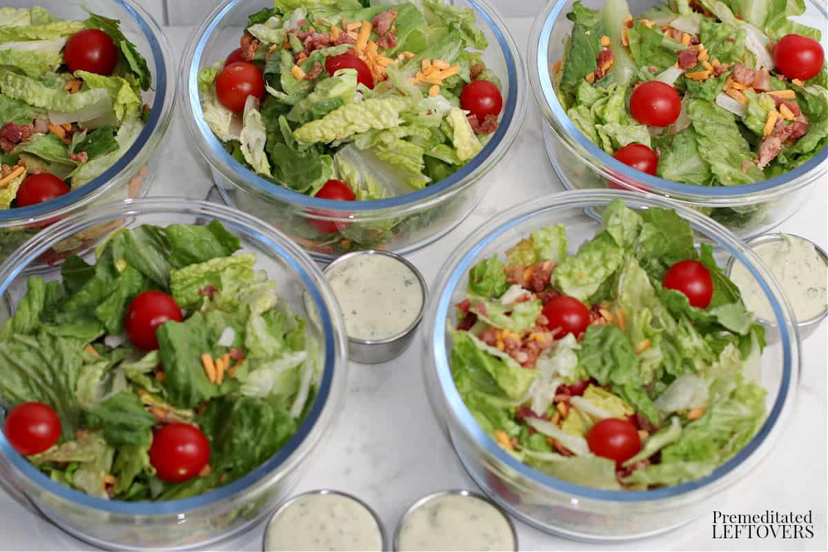 meal prep BLT salads in glass bowls with avocado ranch dressing.
