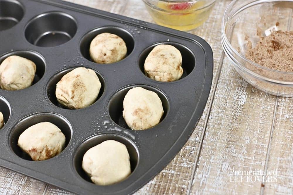 Place the rolls in a muffin tin. Brush the rolls with some of the remaining melted butter. then sprinkle the remaining cinnamon sugar over the rolls.