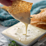 Delicious white queso dip dripping from a crispy tortilla chip.