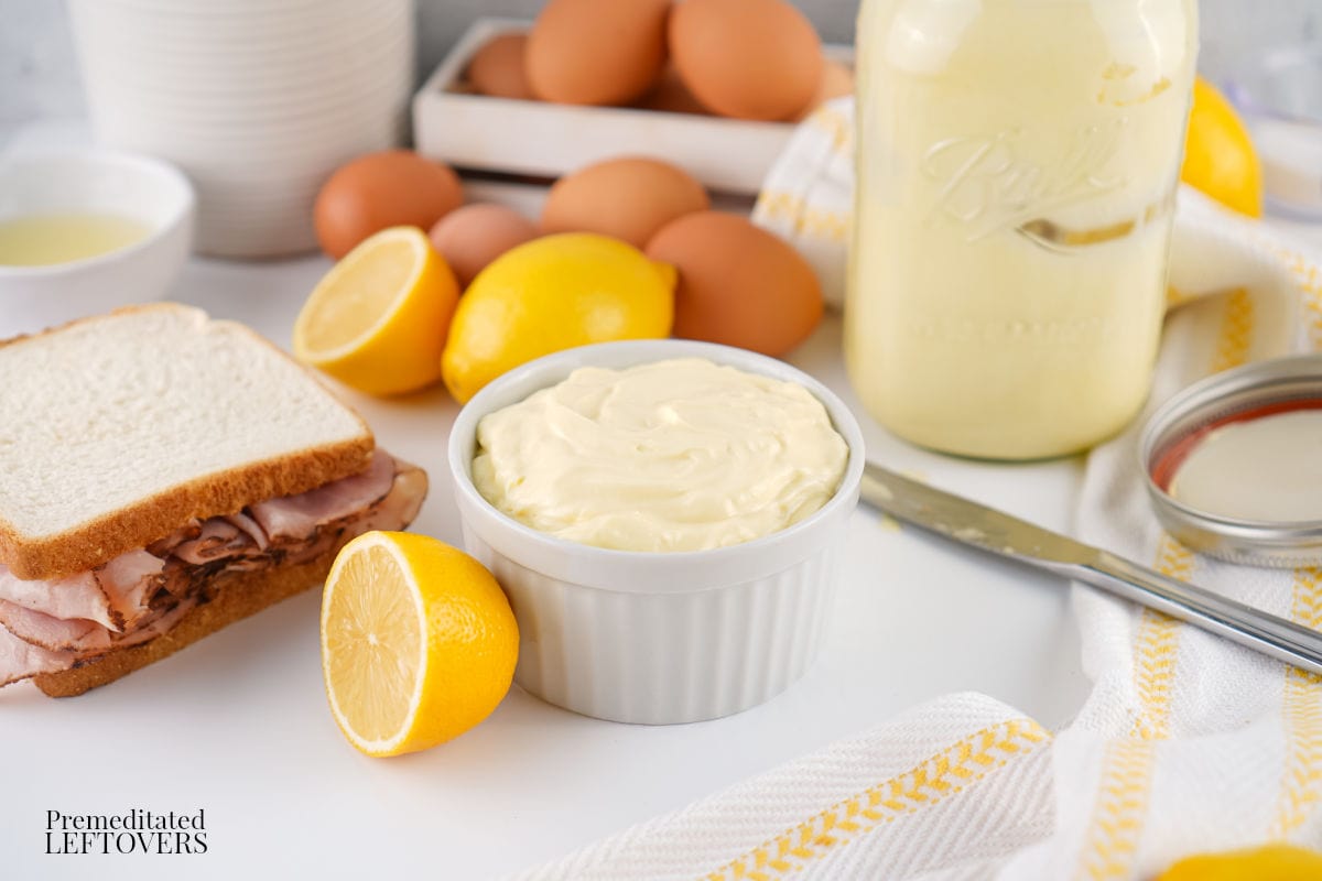 Homemade Mayonnaise Recipe on a counter with sandwich, lemons, eggs