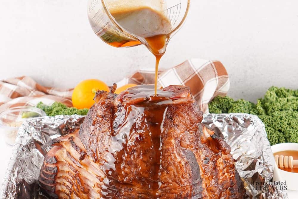 pouring honey glaze over the ham